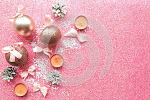 Christmas baubles with bows on pink glitter background.