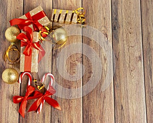 Christmas baubles, fir branches, gift, balls for the Christmas tree, candy canes, paper for text on a brown wooden table.