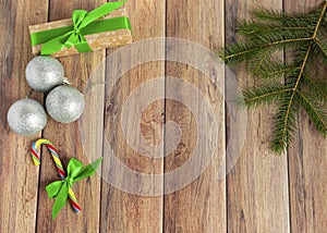 Christmas baubles, fir branches, gift, balls for the Christmas tree, candy canes, paper for text on a brown wooden table.