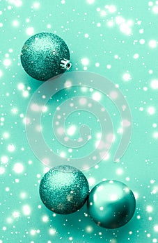 Christmas baubles on green background with snow glitter, luxury winter holiday card