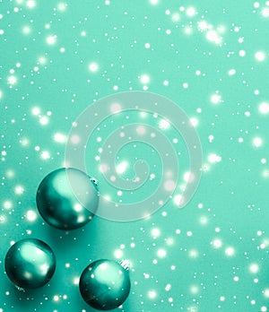 Christmas baubles on green background with snow glitter, luxury winter holiday card