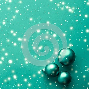 Christmas baubles on green background with snow glitter, luxury winter holiday card