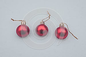 Christmas baubles in the snow, three red baubles