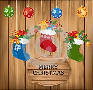 Christmas baubles and stoking with fir branch, candy cane and gifts on wooden background with Merry Christmasgreetings