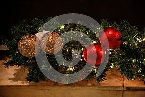 Christmas baubles on wreath made of fir branches. Twigs pine, red and gold Christmas balls as decorations for New Year holidays.