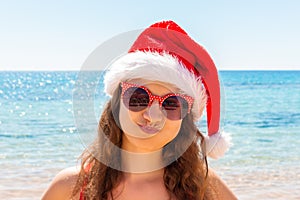 Christmas beach vacation travel portrait woman wearing Santa hat enjoying christmas on tropical beach