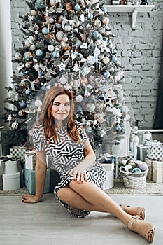 Christmas. Beautiful smiling woman Red long hair. Elegant over christmas tree lights background. happy new year.