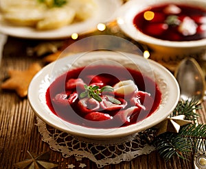 Christmas beetroot soup, borscht with small dumplings with mushroom filling in a ceramic bowl on a wooden table, top view.