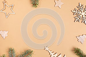 Christmas beige background with frame of wooden festive decorations - Xmas toys and fir tree twigs with copy space.