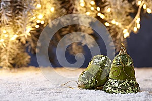 Christmas bells on snowy table on tree lights background