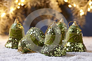 Christmas bells on snowy table on tree lights background