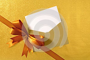 Christmas or birthday card, diagonal gold gift ribbon bow, blank card and envelope, copy space