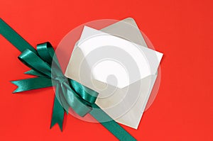 Christmas or birthday card on red gift paper background with green ribbon bow diagonal, copy space