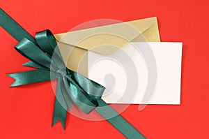 Christmas or birthday card on red gift wrap paper background, green gift ribbon bow, white copy space