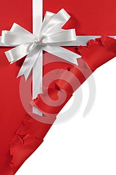 Christmas or birthday white satin gift ribbon bow on torn open red paper background