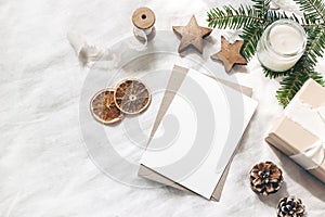 Christmas blank greeting card mock-up scene. Festive winter wedding composition. Craft envelope, pine cone, gift box