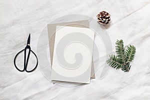 Christmas blank greeting card mock-up scene. Festive winter wedding composition. Envelope, pine cone, black vintage