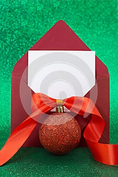 Christmas blank greeting card mockup with red glitter ball with bow and ribbon on sparkling green background. Envelope with letter