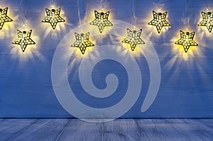 Christmas blank interior with glow lights yellow stars on indigo blue wood background.