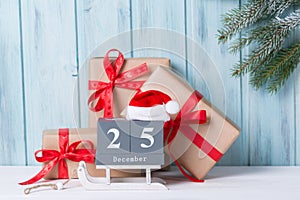 Christmas block calendar with 25 December and gift boxes, wooden background with fir tree branch
