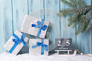 Christmas block calendar with 25 December and gift boxes, wooden background with fir tree branch