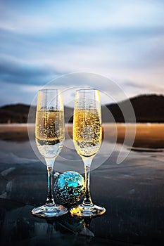 Christmas blue balloons and two glasses of champagne. Champagne glasses stand on the ice of the frozen Lake Baikal.