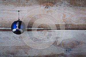 Christmas blue bauble hanging from a line by a peg over wooden b