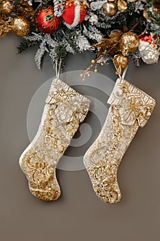Christmas boots hanging on a Christmas tree wreath and toys on a gray wall background. Socks on the fireplace