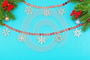 Christmas border with branches of spruce, snowflakes, holidays bows, christmas toys on a blue background