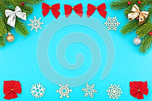 Christmas border with branches of spruce, snowflakes, holidays bows, christmas toys on a blue background