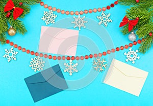 Christmas border with branches of spruce, snowflakes, holidays bows, christmas toys and envelopes on a blue background