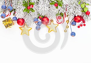 Christmas border composition with holly berries, red baubles, golden garland and green Xmas tree twig isolated on white background