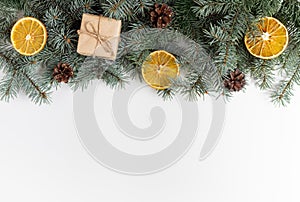 Christmas border with fir branches, cones, gifts and dried oranges on a white background