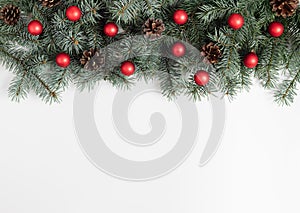 Christmas border with fir branches, red balls and cones on a white background