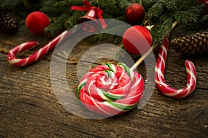 Christmas border with fir tree branches, cones, christmas decorations and candy cane on rustic wooden boards