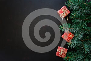 Christmas Border. Fir tree branches with gift boxes on dark wooden background.