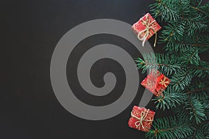 Christmas Border. Fir tree branches with gift boxes on dark wooden background. Top view. Copy space.