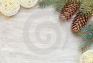 Christmas border or frame corner design with fir branch and pinecones on rustic wooden background.