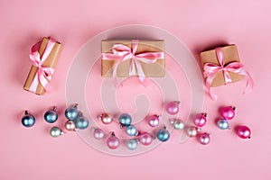 Christmas border with gift boxes, balls, decoration and sequins on pink table top view.