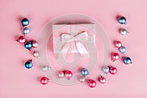 Christmas border with gift boxes, balls, decoration and sequins on pink table top view
