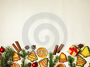 Christmas border. Gingerbread cookies, spices, christmas tree branches and decorations on white wooden background. Top