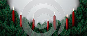 Christmas border made of evergreen branches decorated with burning candles