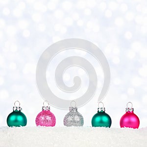 Christmas border of pastel ornaments in snow with twinkling lights