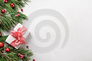 Christmas border with red gift, evergreen branches on white. Xmas greeting card with copy space. View from above. Flat lay style