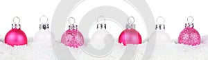 Christmas border of pink and white ornaments in snow isolated on white