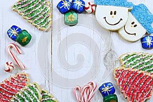 Christmas border of sweets, including cookies, peppermints and chocolates on a rustic wooden background.