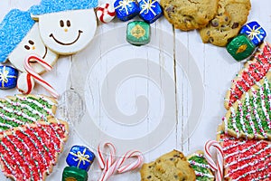 Christmas border of sweets, including cookies, peppermints and chocolates on a rustic wooden background.