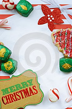 Christmas border of sweets, including cookies, peppermints and chocolates on a rustic wooden background. photo