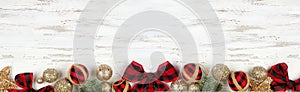 Christmas bottom border of red and black gingham ornaments, branches and gold baubles on a white wood banner background