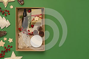 Christmas box with cosmetics on green background